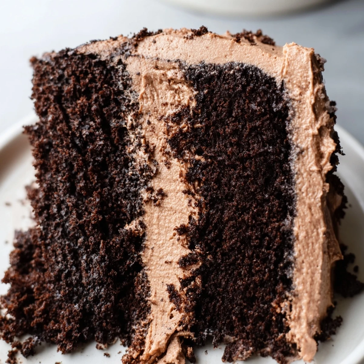 A slice of Chocolate Cake with Frosting reveals velvety crumb and glossy frosting, perfect with a cold glass of milk.