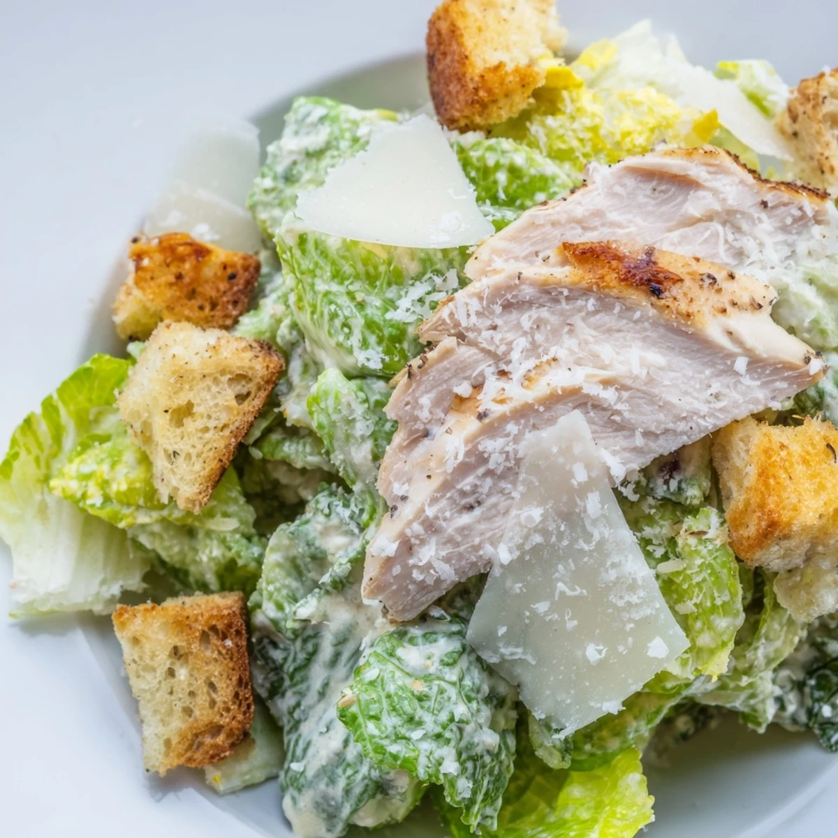 Sliced grilled chicken breast and golden croutons rest on fresh romaine lettuce with rich Caesar dressing and parmesan cheese.