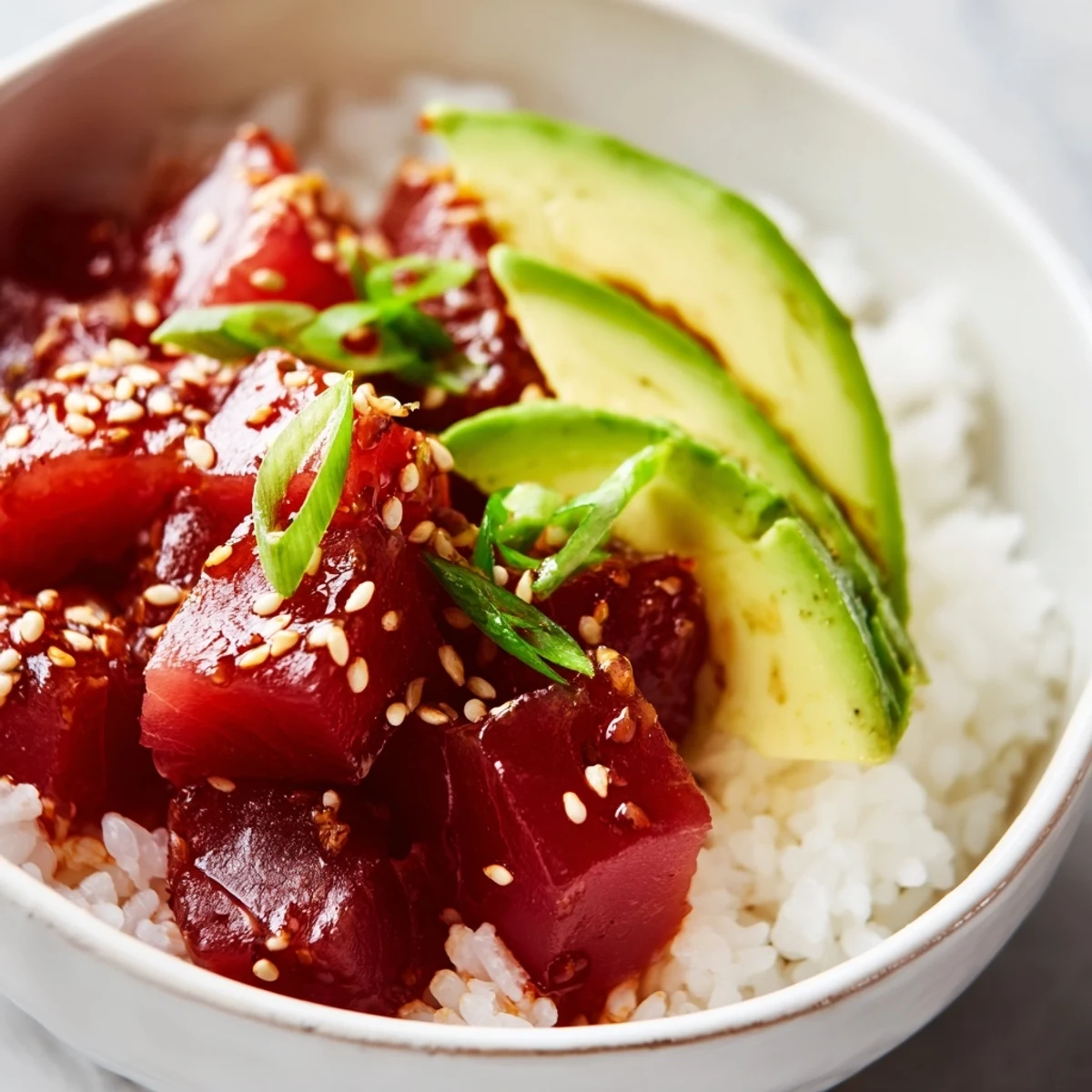 A vibrant, deconstructed view of a Spicy Tuna Poke Bowl featuring creamy avocado and spicy tuna over rice.
