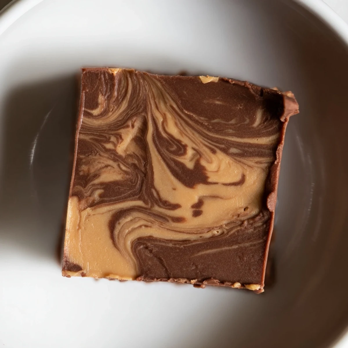 Creamy chocolate and peanut butter fudge squares with a marbled swirl, served chilled on a dessert plate.