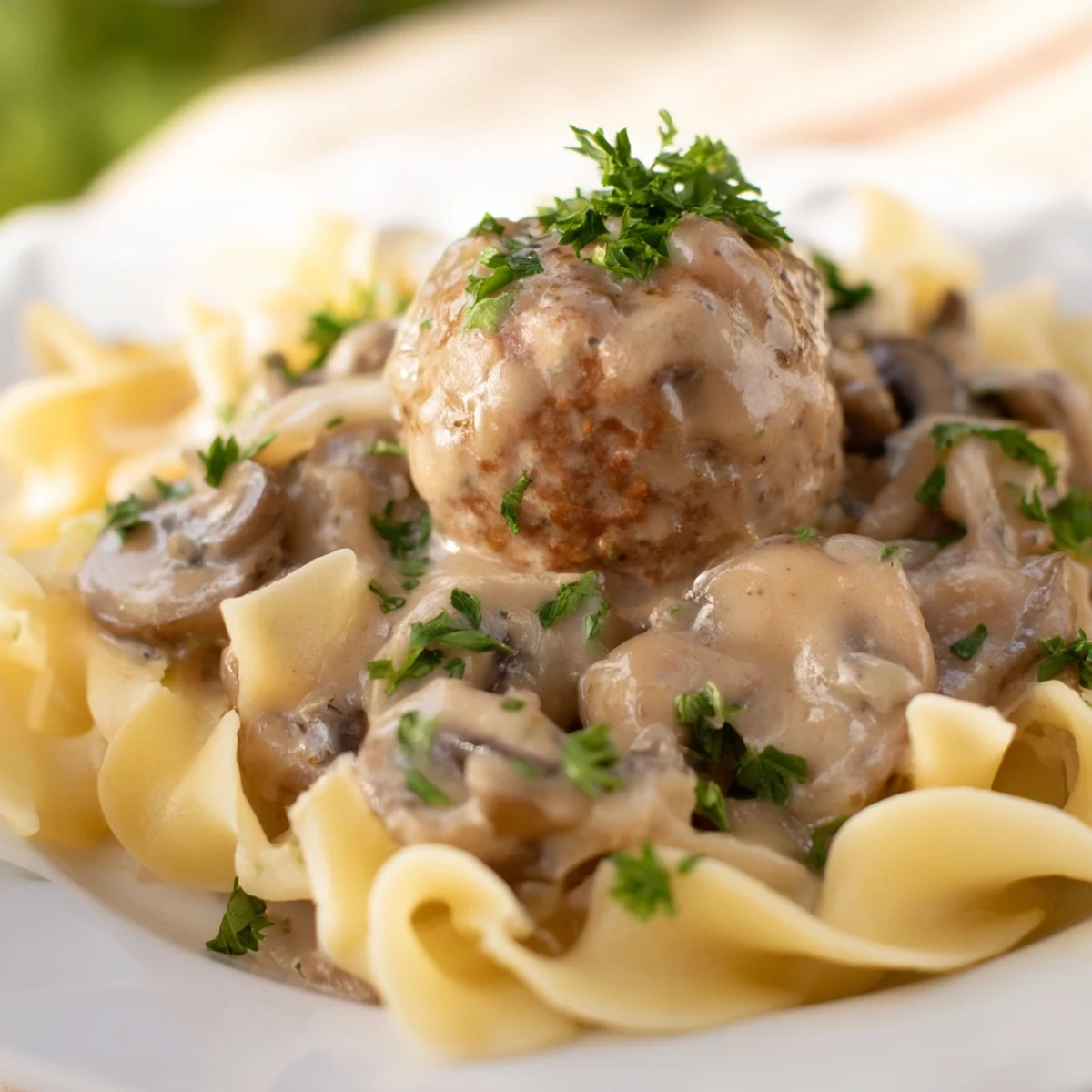 A steaming plate of Turkey Meatball Stroganoff features tender meatballs, rich mushroom gravy, and pasta for a hearty meal.