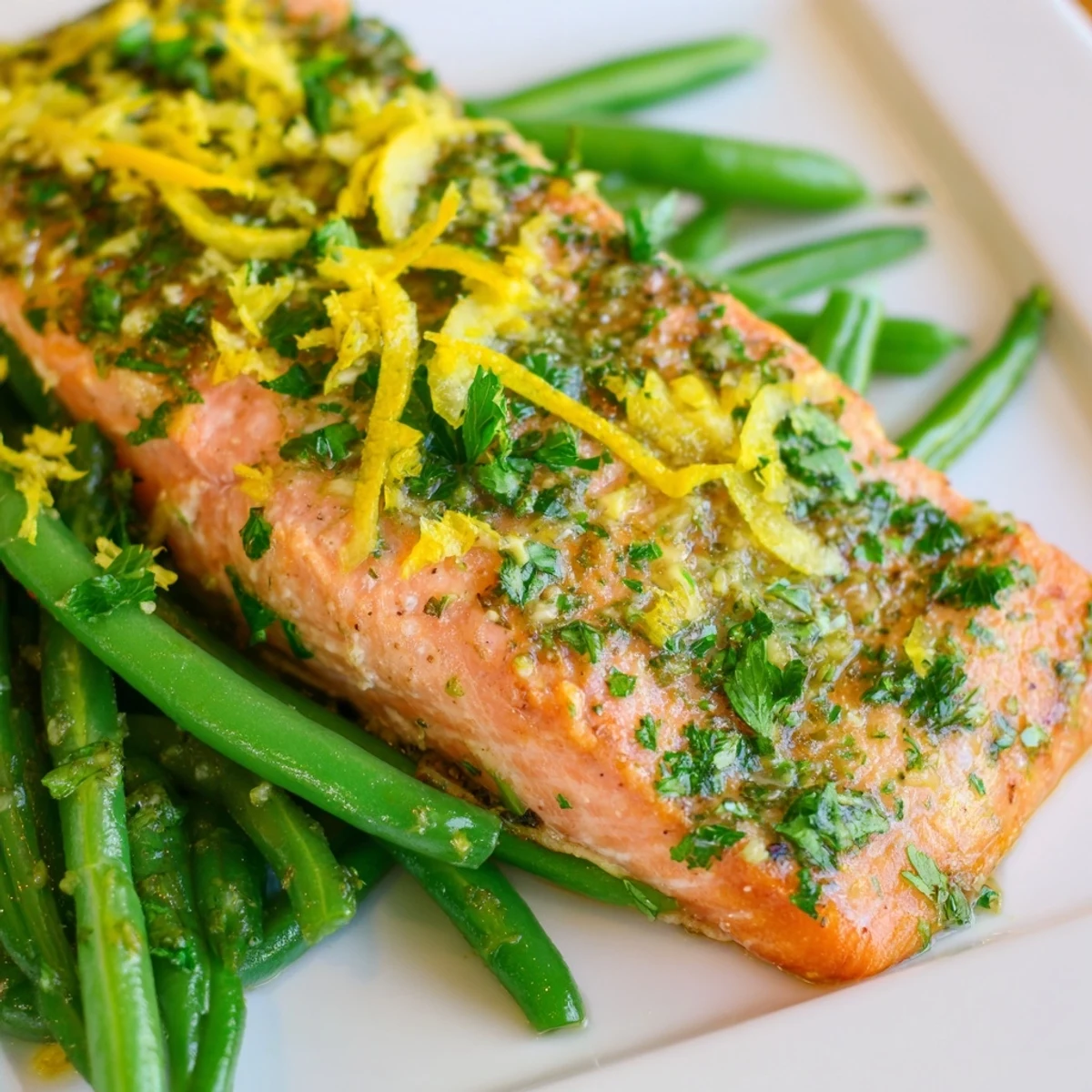 Golden-brown salmon fillets roasted alongside bright green beans on a sheet pan, garnished with fresh parsley and lemon wedges.  
