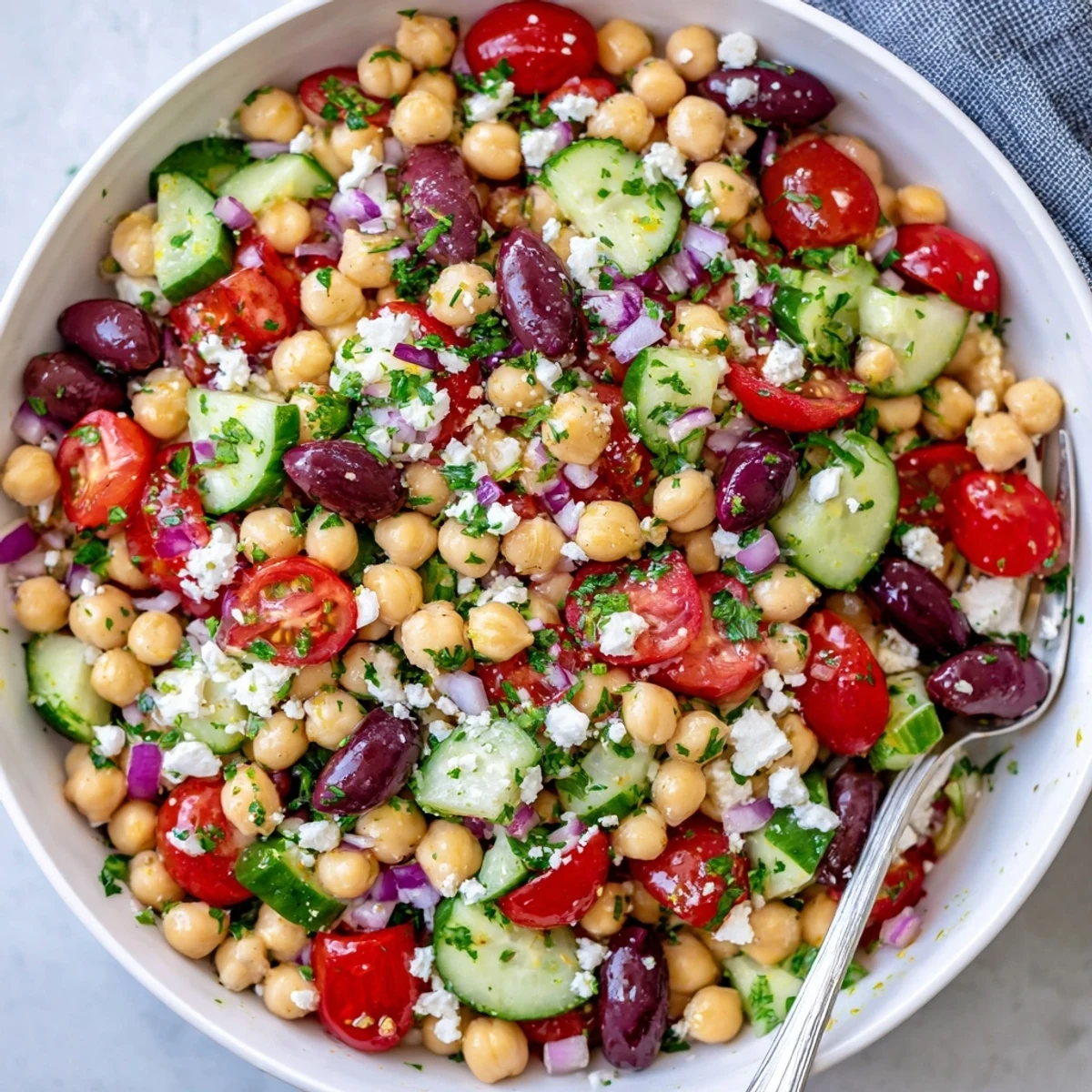 Vibrant Mediterranean Chickpea Salad tossed with cucumbers, red onion, and parsley, drizzled with lemon-oregano vinaigrette.