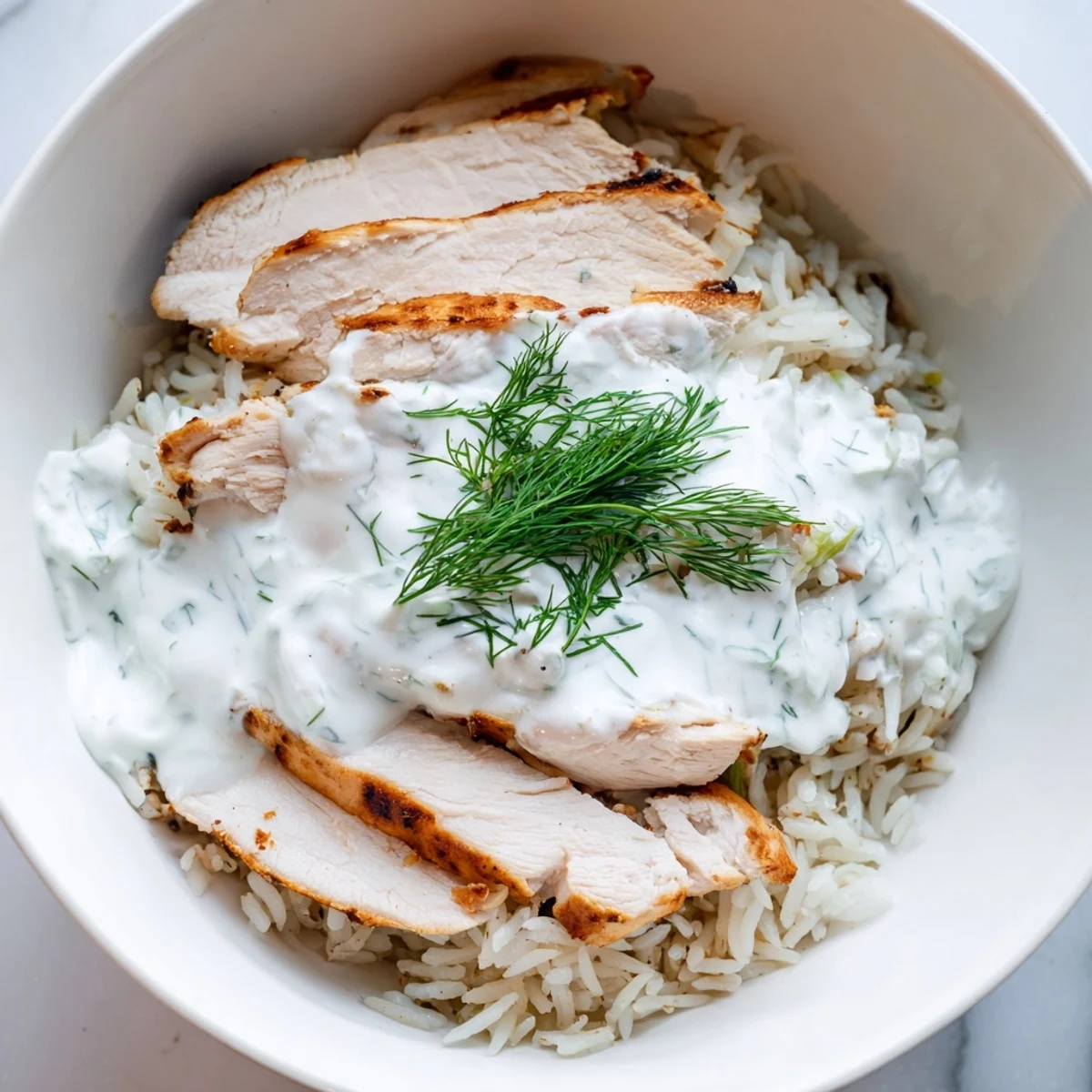 Golden-brown grilled chicken slices are piled over fluffy rice in this vibrant Greek Chicken Gyro Bowl, garnished with fresh veggies and creamy tzatziki sauce.