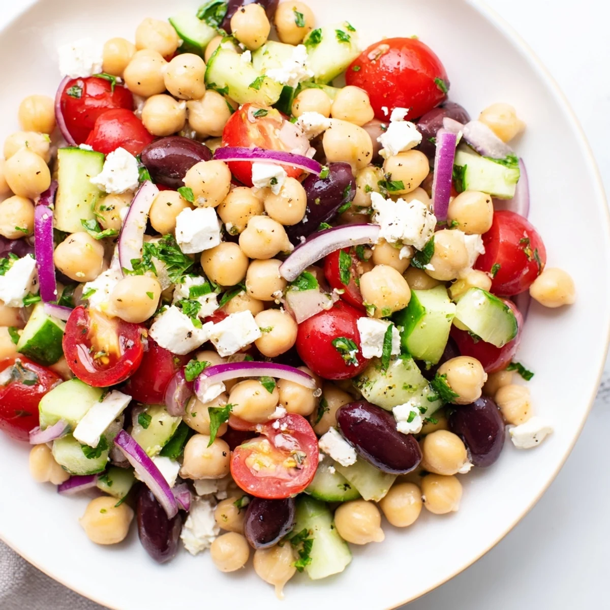 Freshly tossed Mediterranean Chickpea Salad with Feta, featuring crumbled cheese, parsley, and a glistening lemon-olive oil dressing for a zesty finish.
