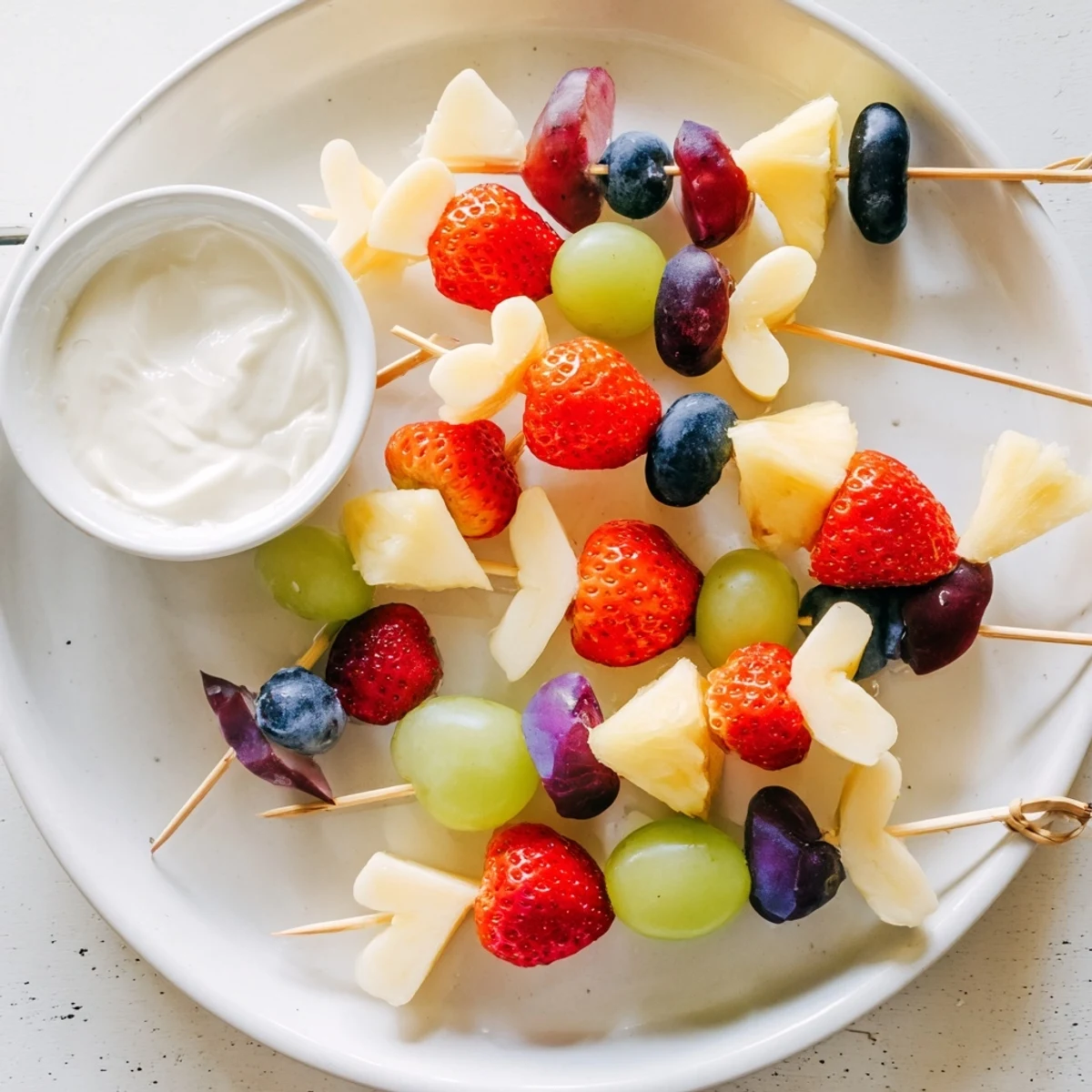 Vibrant Sweetheart Fruit Kabobs with Yogurt dip, featuring fresh strawberries, grapes, and heart-shaped melon on skewers.