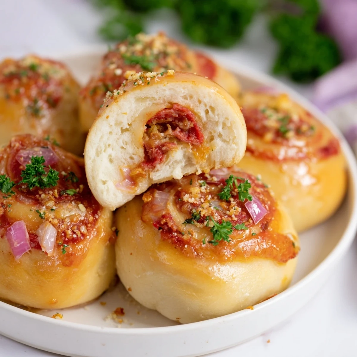 Freshly baked Super Bowl Pizza Rolls dusted with parsley, with a crispy crust and colorful pepper and onion filling.