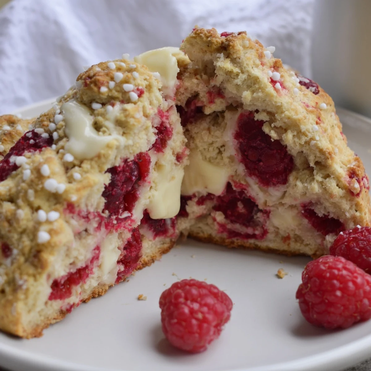 Freshly baked Raspberry White Chocolate Scones on a wooden board, showcasing golden crusts and melty white chocolate chips.
