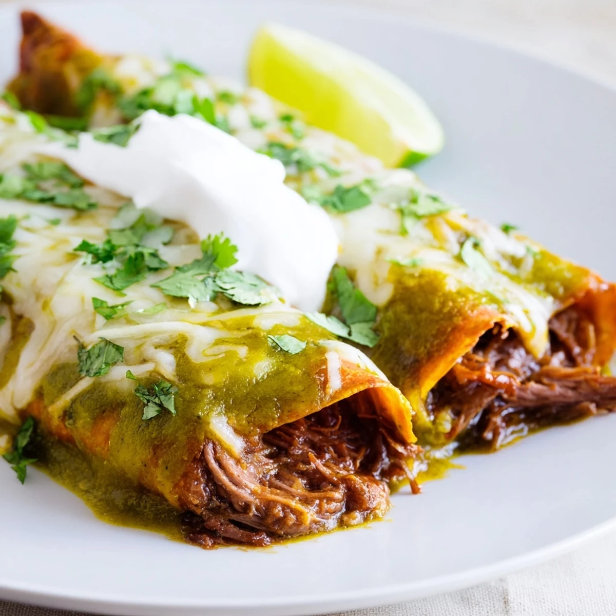 Beef Enchiladas with Green Sauce feature shredded beef and melted cheese under tangy green sauce, served warm from the oven.