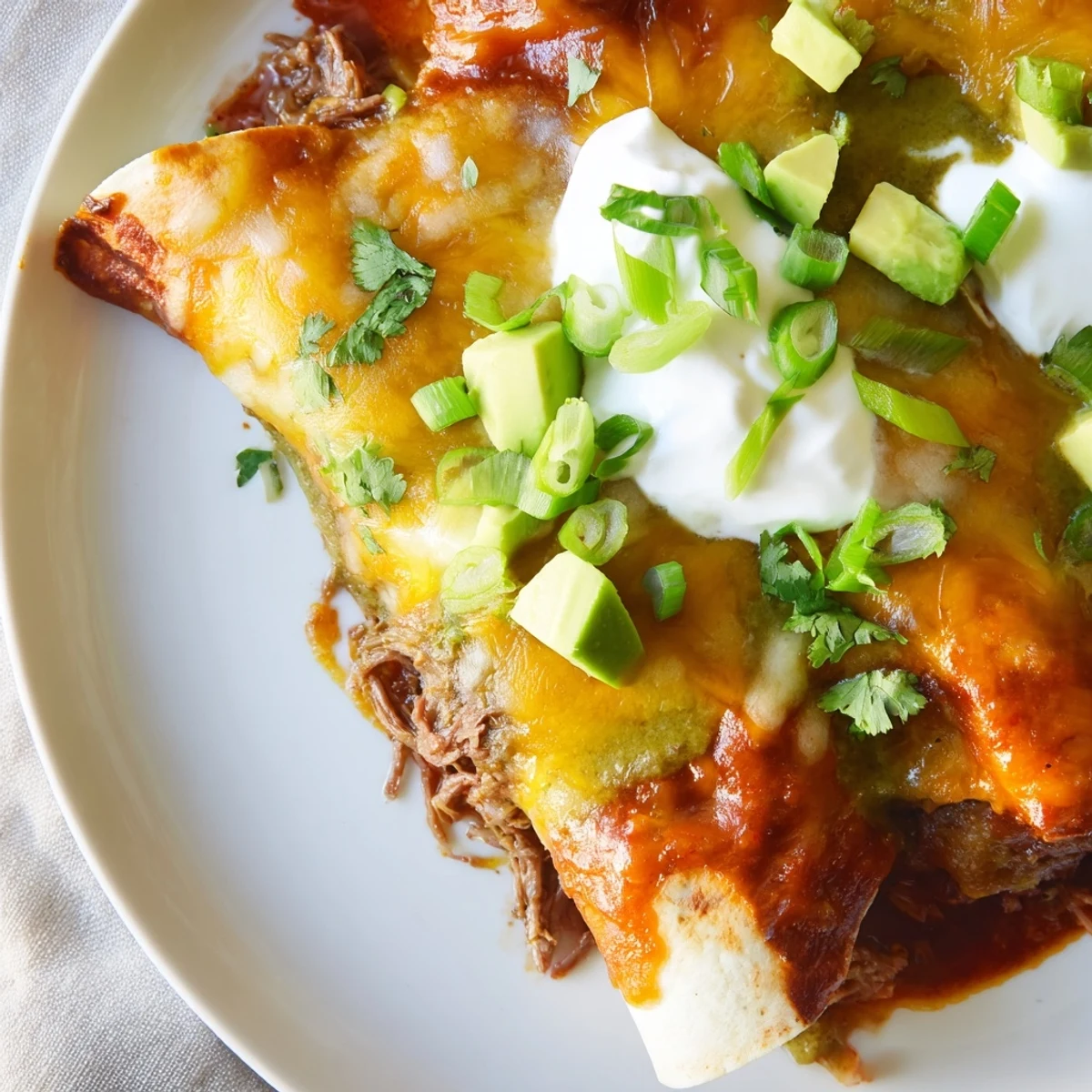 Golden-brown Beef Enchiladas with Green Sauce bubbling with melted cheese in a baking dish.  