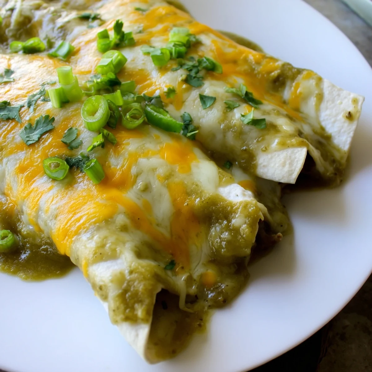 Golden-brown beef enchiladas smothered in creamy green chili sauce and topped with melted cheese.
