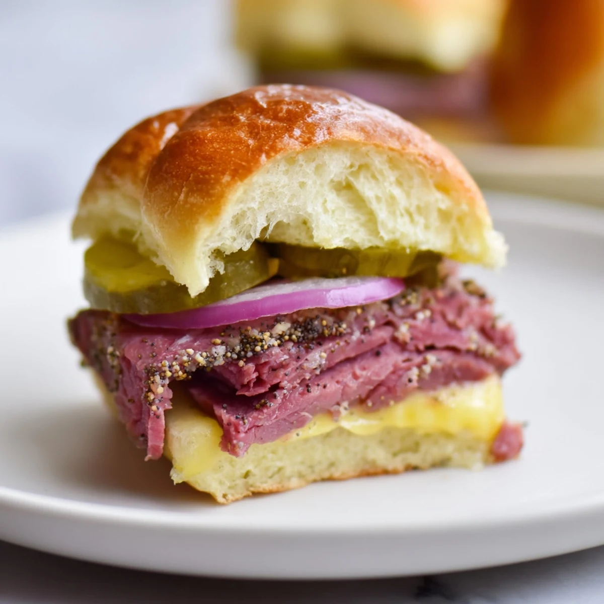 A close-up of golden-baked Corned Beef Sliders with Swiss Cheese stacked high on a platter for game day.