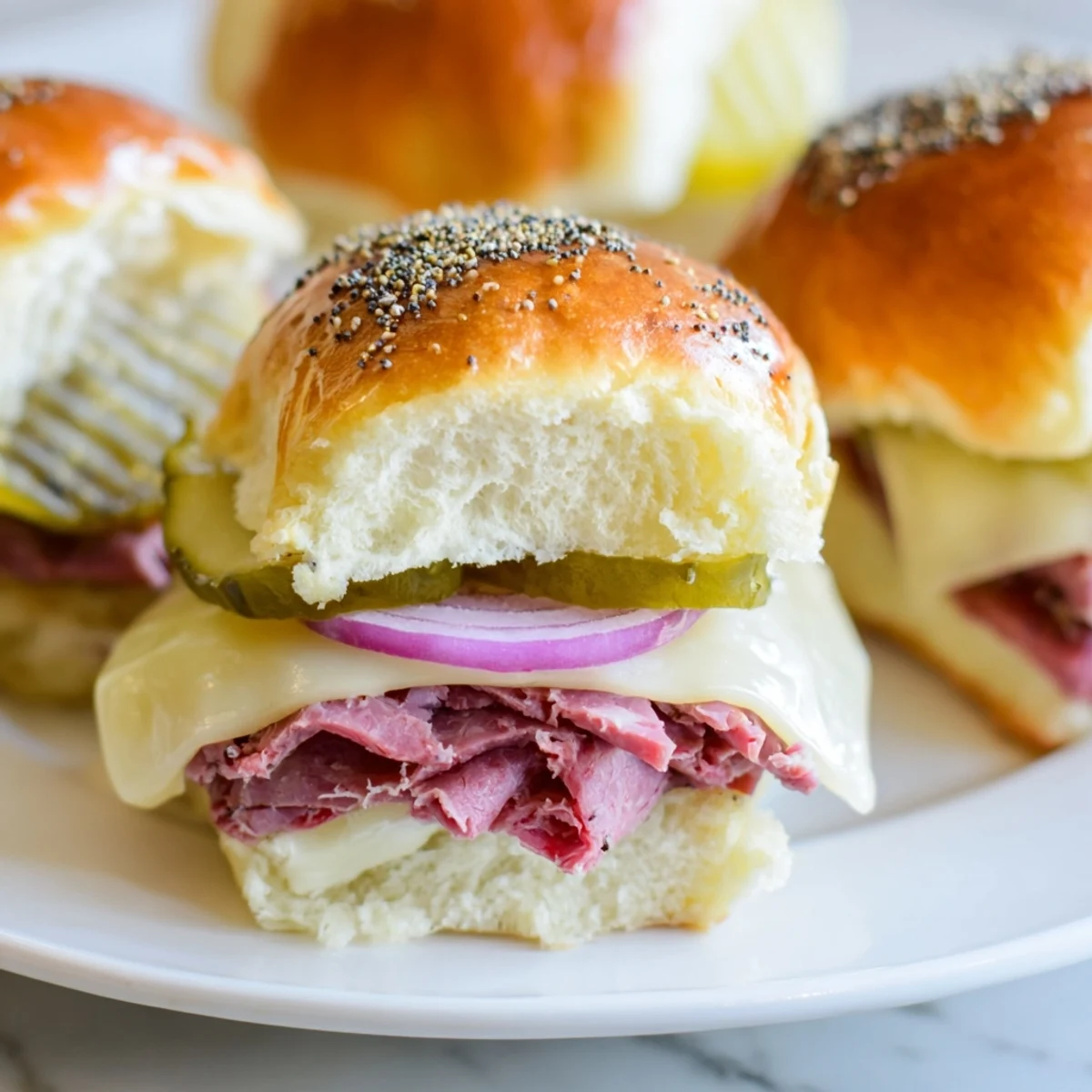 Freshly baked Corned Beef Sliders with Swiss Cheese featuring tender meat, melty cheese, and poppy seed butter topping.