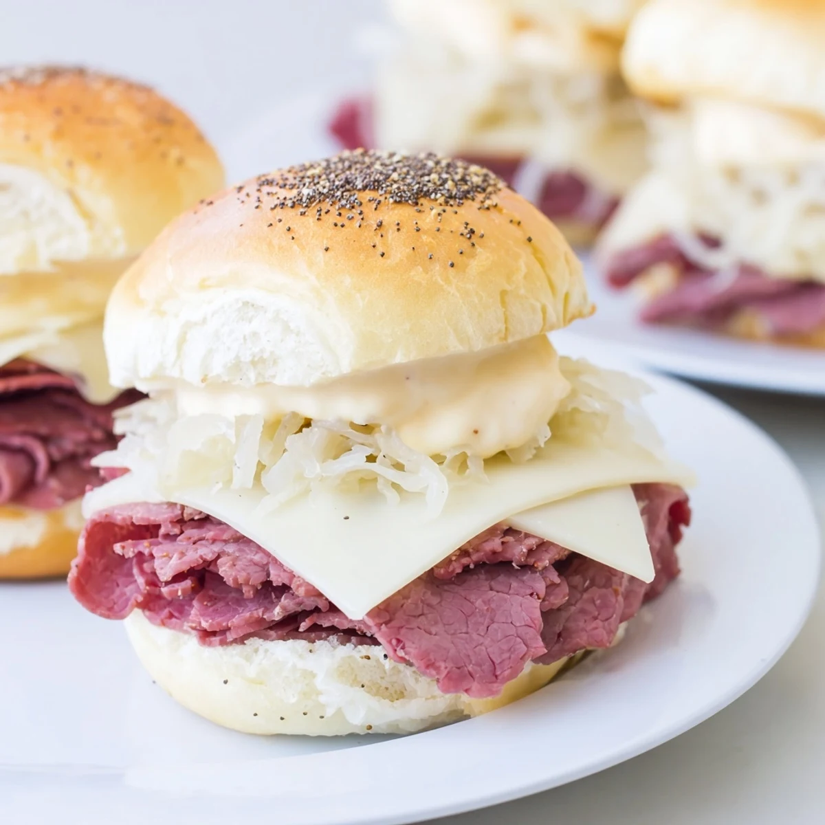 Corned Beef Sliders with Cheese stacked high with tender meat and sauerkraut, baked until warm and bubbly on a festive platter.