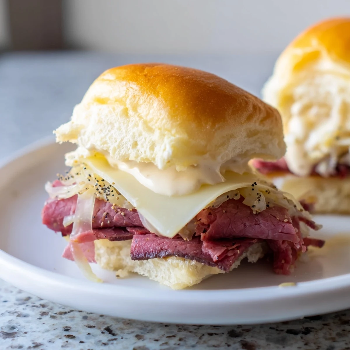 Golden Corned Beef Sliders with Cheese on soft buns, topped with tangy sauce and melty Swiss for a savory party bite.