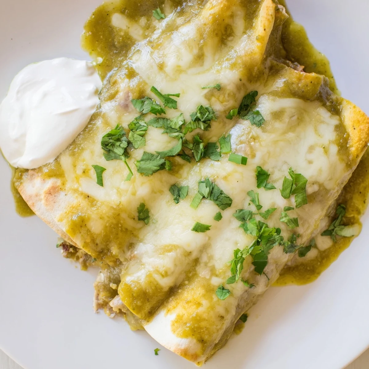 Tender ground beef filling inside warm tortillas, topped with tangy green sauce and fresh cilantro garnish.