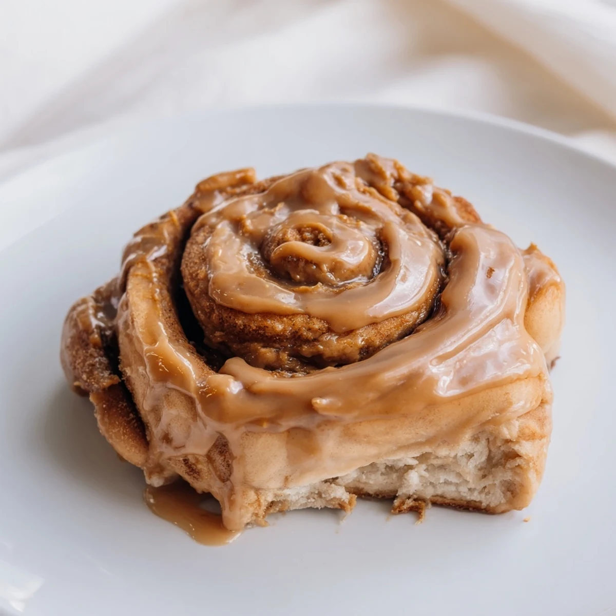 Freshly baked Soft and Gooey Biscoff Cinnamon Rolls swirled with cookie butter filling on a white plate.