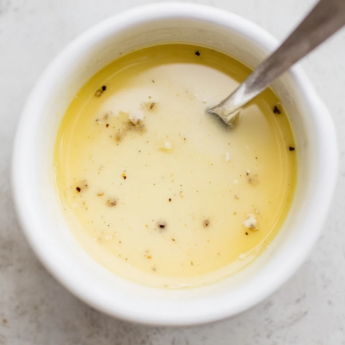 Creamy Lemon Dijon Dressing drizzled over a fresh green salad garnished with herbs.