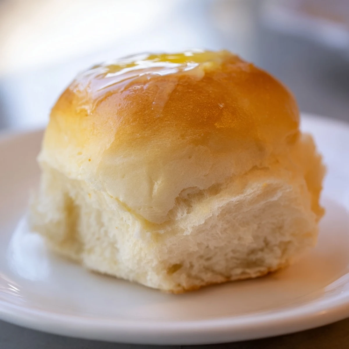 Freshly baked Best Vegan Dinner Rolls with golden-brown tops and soft, fluffy interiors on a rustic wooden board.