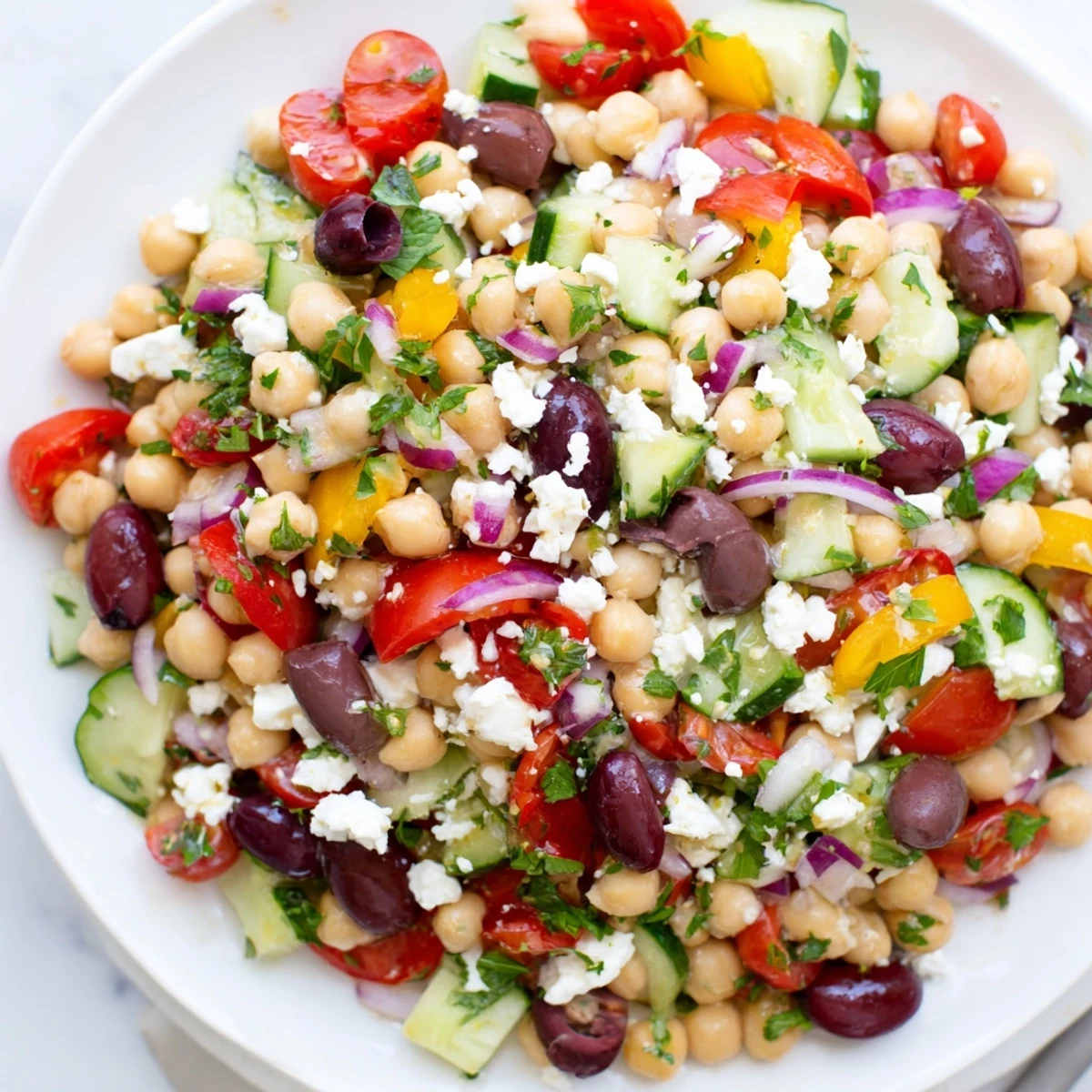 This Mediterranean Dense Bean Salad showcases colorful beans, cucumber, and tomatoes, garnished with mint and dressed in lemony vinaigrette.