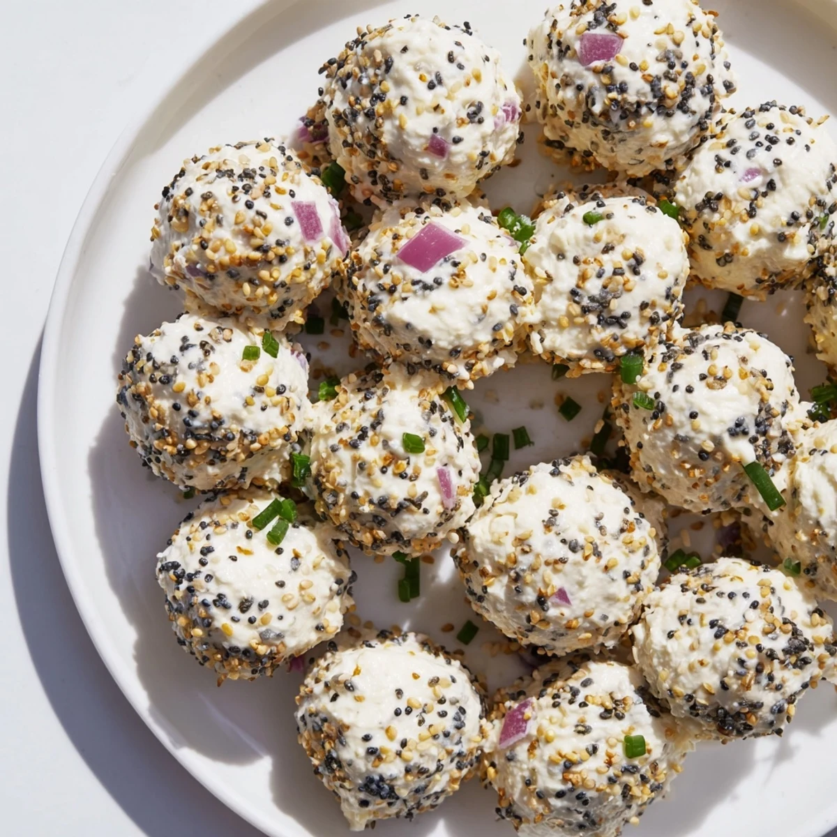 A hand holding a single Everything Bagel Cottage Cheese Bite with creamy cottage cheese filling, served alongside crisp cucumber slices for a fresh, savory bite.
