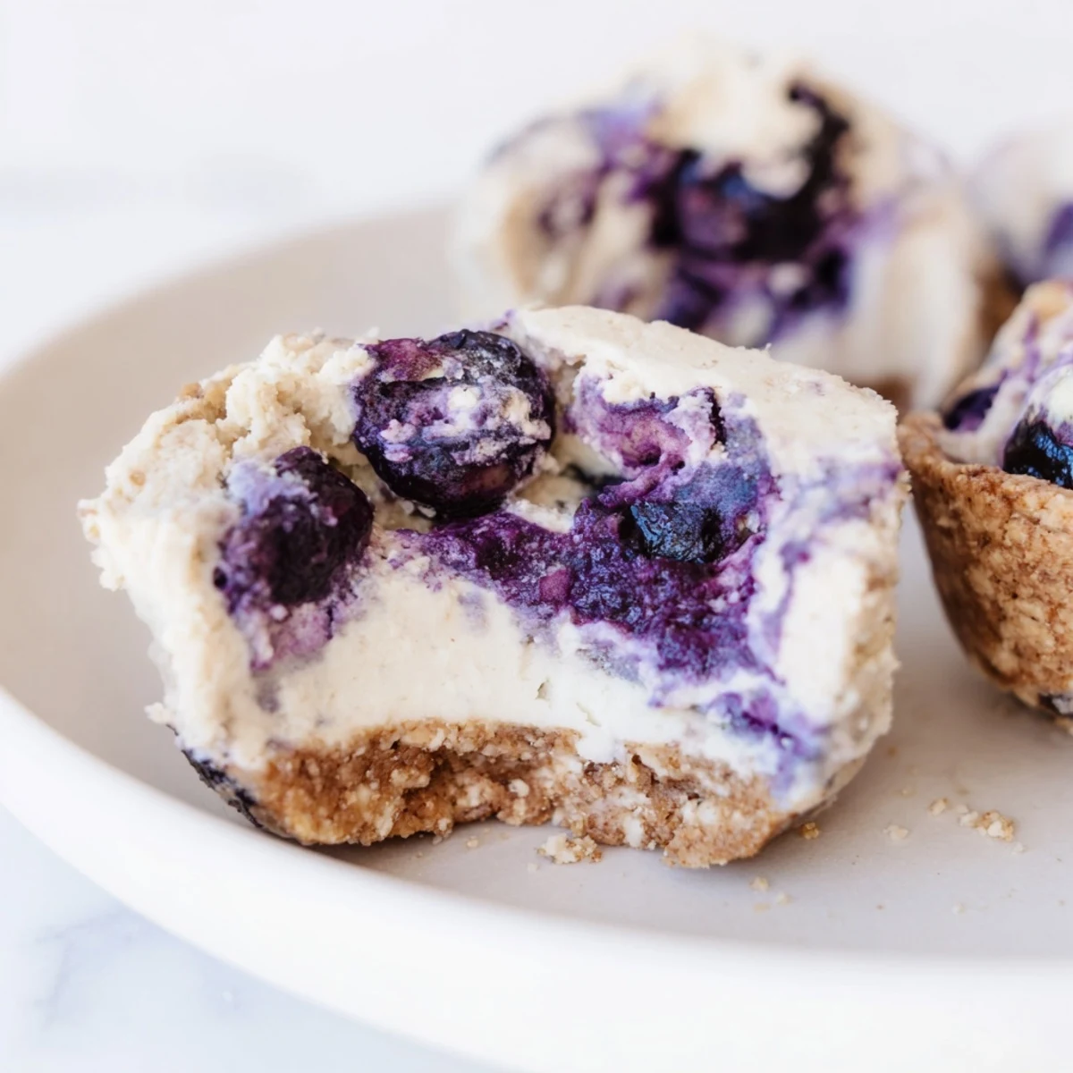 Close-up of Blueberry Cheesecake Protein Bites on a wooden board, showing creamy filling and juicy blueberry swirls.