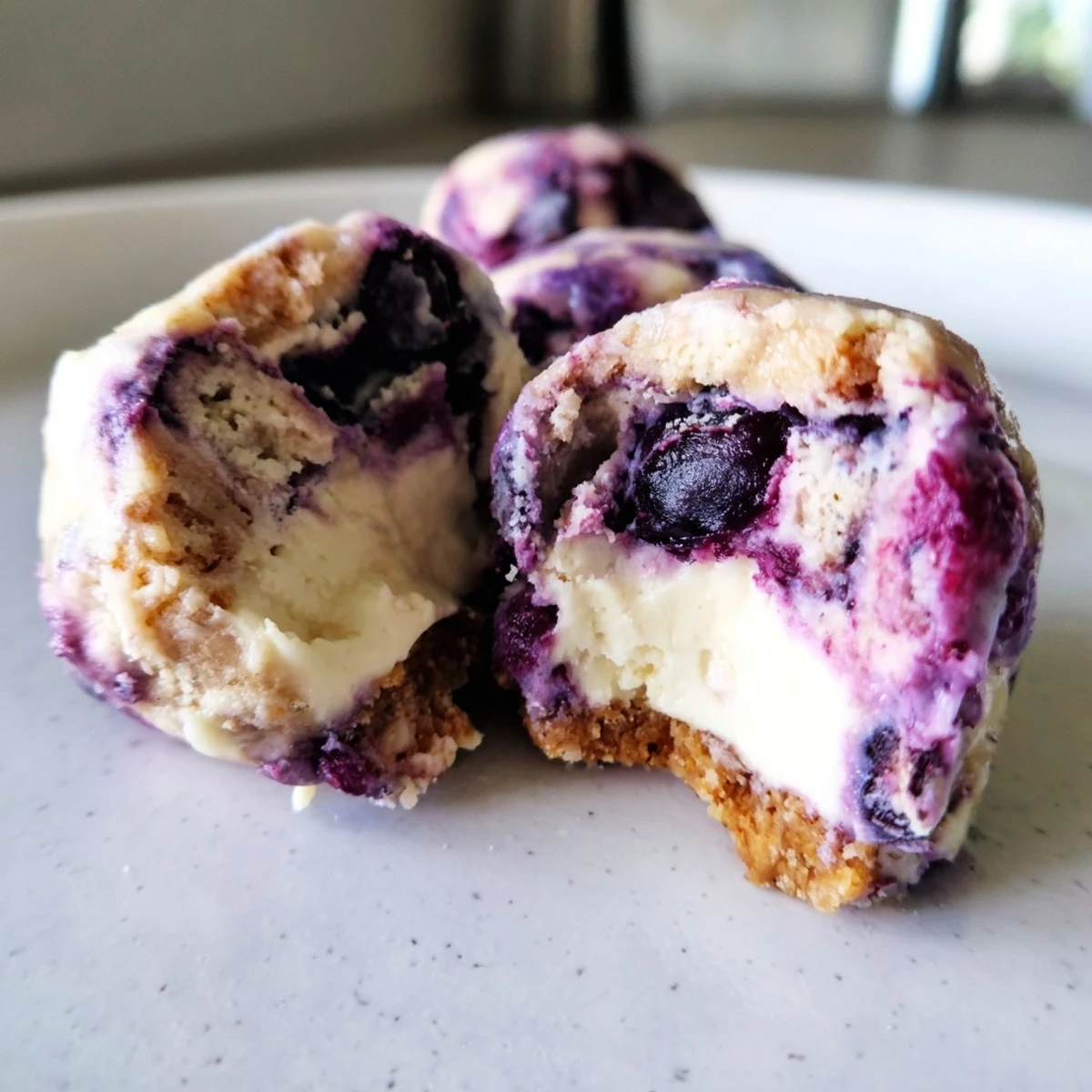 A single Blueberry Cheesecake Protein Bite with almond flour base and tangy cream cheese swirl ready to enjoy.