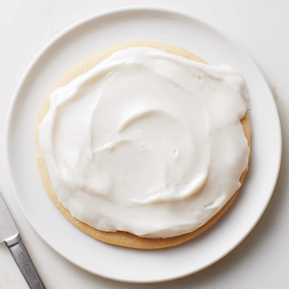 Creamy white Easy Sugar Cookie Frosting in a bowl with a whisk, ready for decorating cookies.