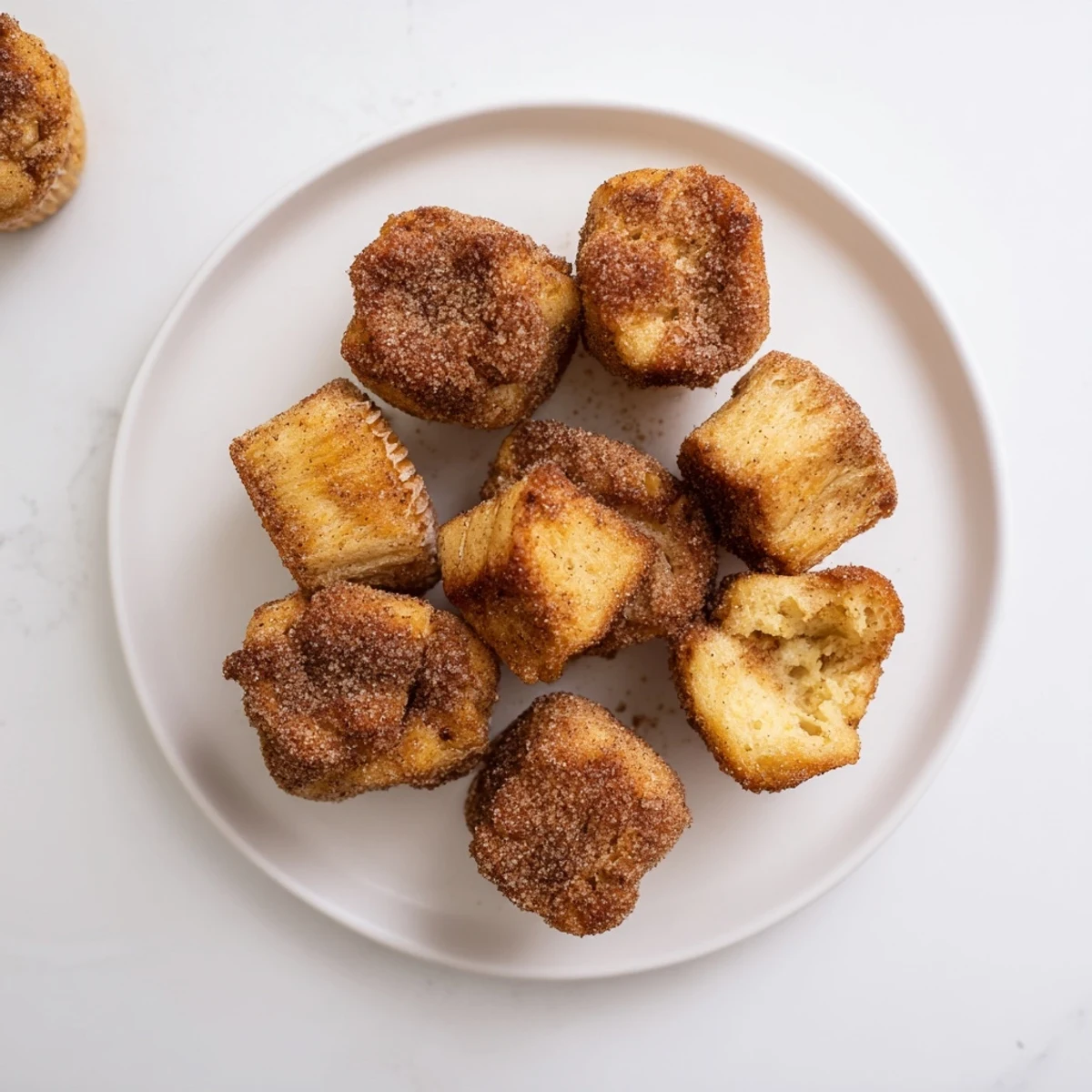 A batch of golden-brown Cinnamon Sugar French Toast Muffins served warm with fresh berries and a drizzle of maple syrup.