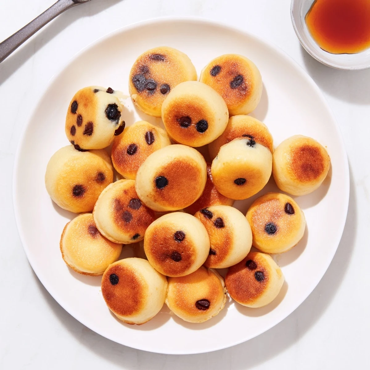 Fluffy golden Pancake Poppers cooling on a wire rack with maple syrup drizzle for dipping.  