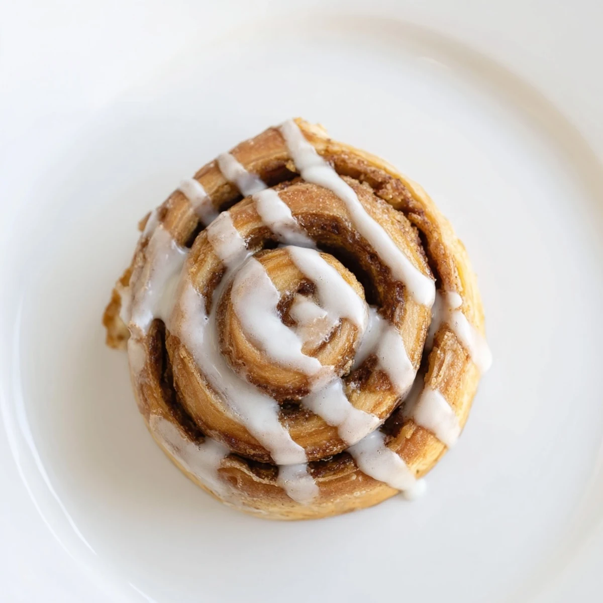 A close-up of Cinnamon Roll Cookies drizzled with sweet vanilla glaze on a wire rack beside a steaming mug of coffee.