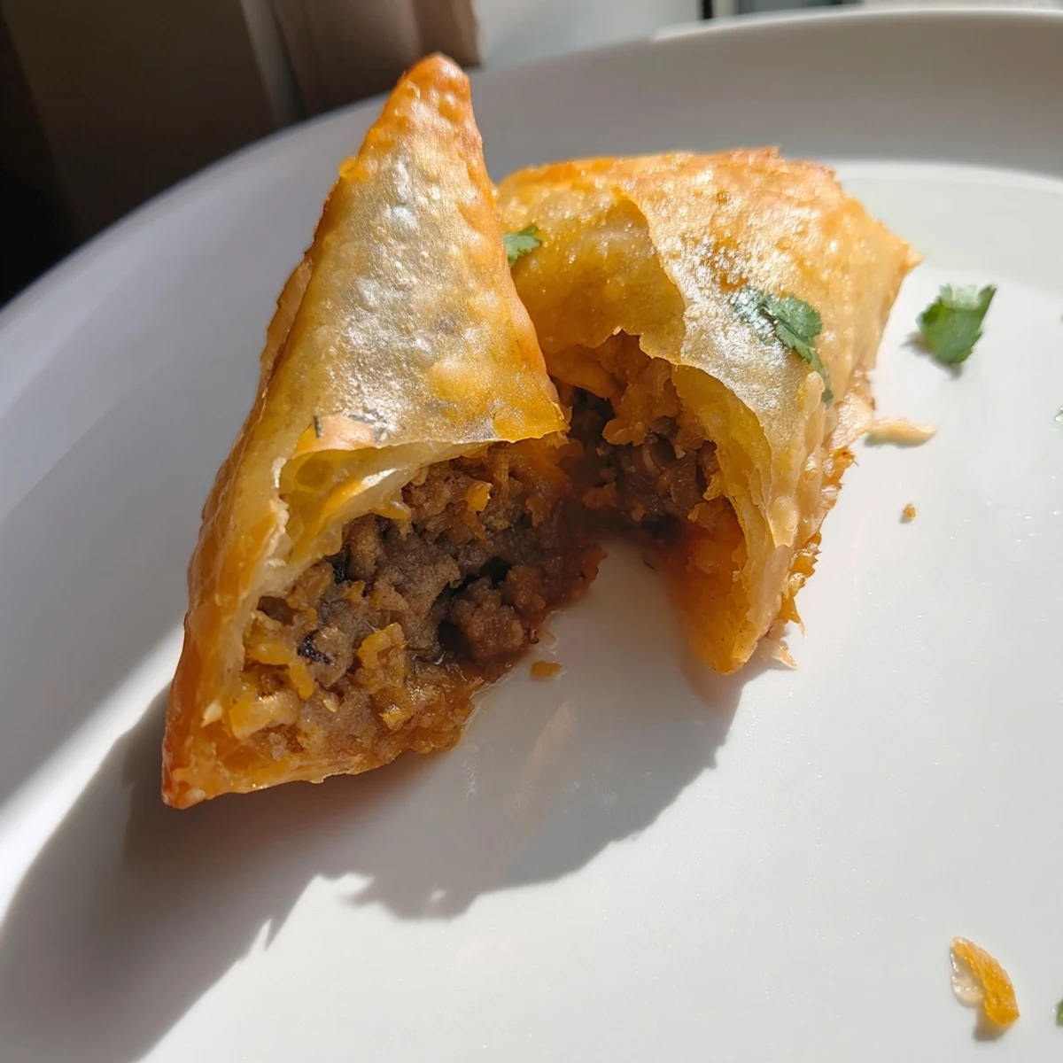 Close up of Spiced Meat Sambusas revealing flaky pastry pockets stuffed with aromatic ground beef and onions.