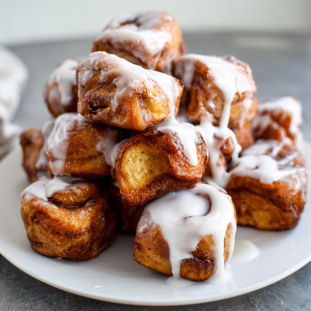 Warm Cinnamon Roll French Toast Bites stacked high, coated in custard and dusted with powdered sugar for brunch.