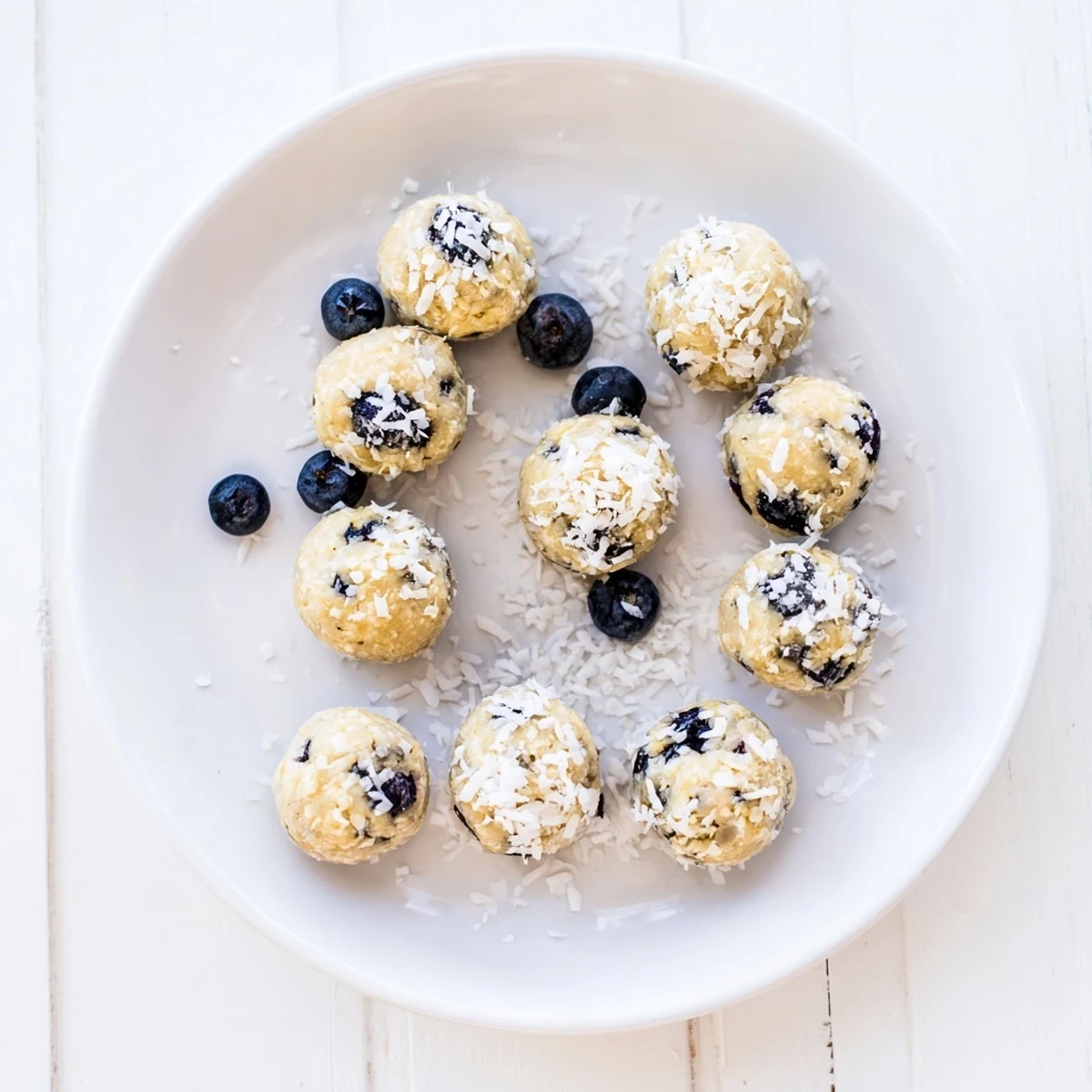 Golden Lemon Blueberry Cottage Cheese Protein Bites on a marble board, garnished with fresh lemon slices and blueberries for a bright, healthy snack.