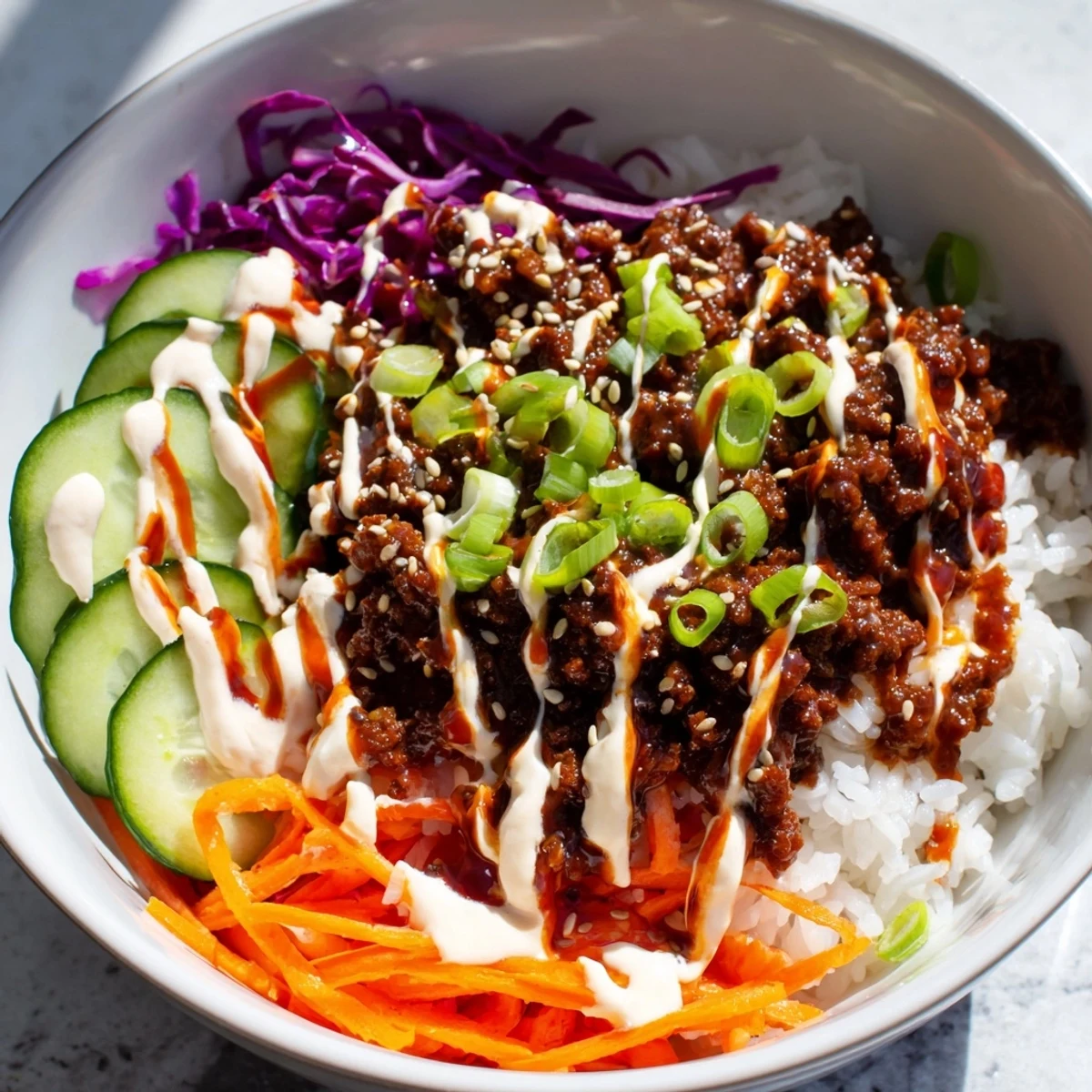 A close-up of the Korean beef bowl reveals tender ground beef, shredded carrots, and creamy spicy mayo. 