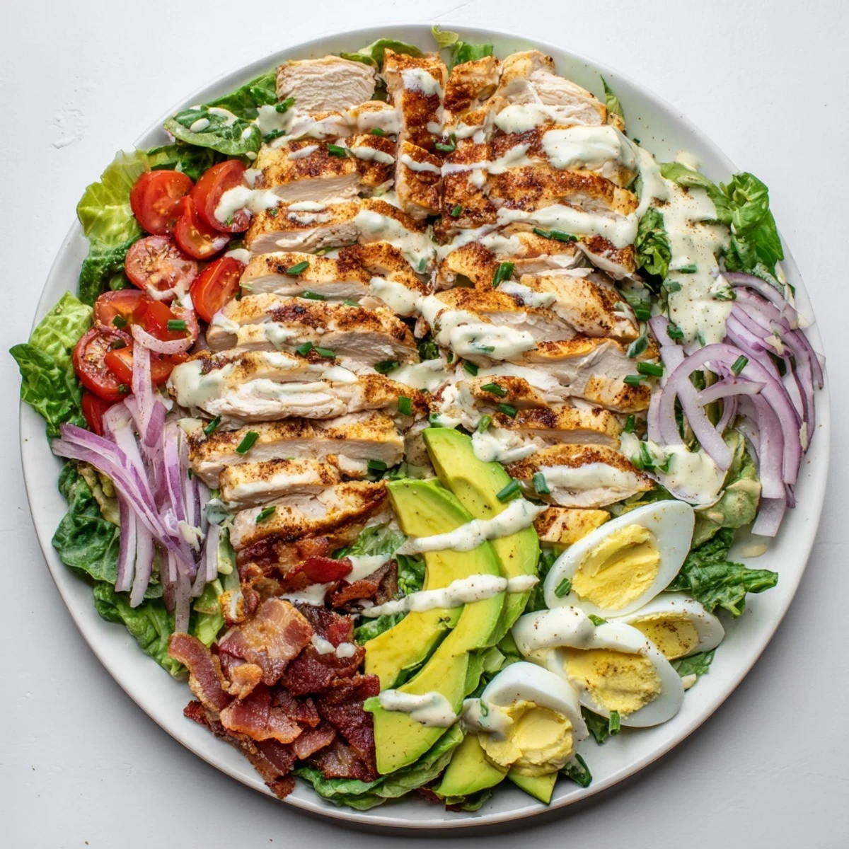 A close-up of the Paleo Grilled Chicken Cobb Salad With Honey Dijon Dressing showing chopped eggs and tangy dressing.