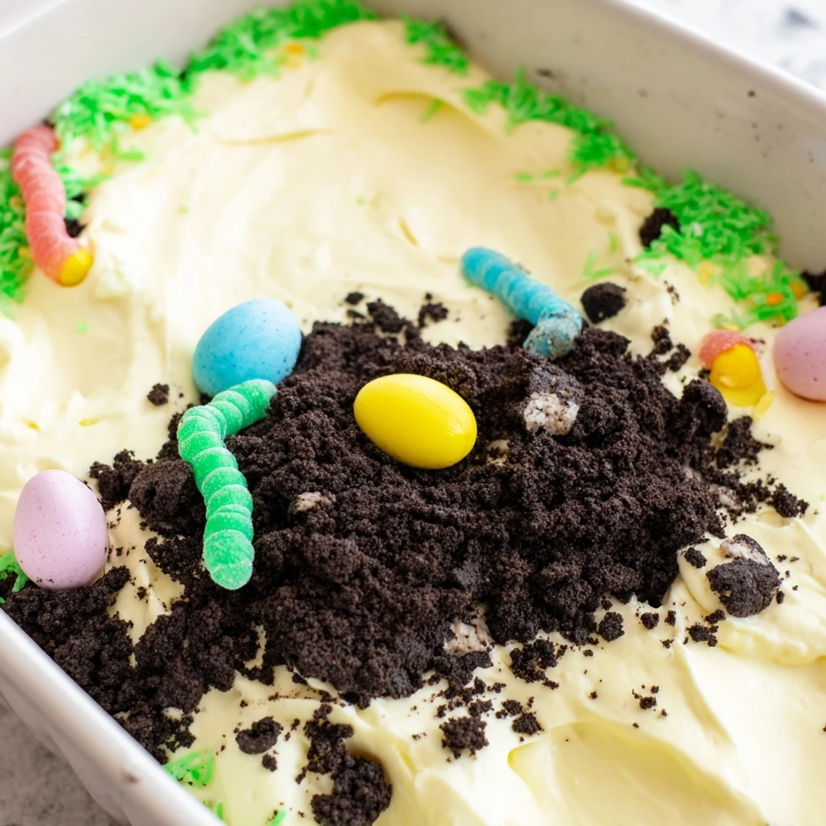 Layered Easter Dirt Cake Casserole in a dish with creamy pudding and chocolate cookie crumbles.