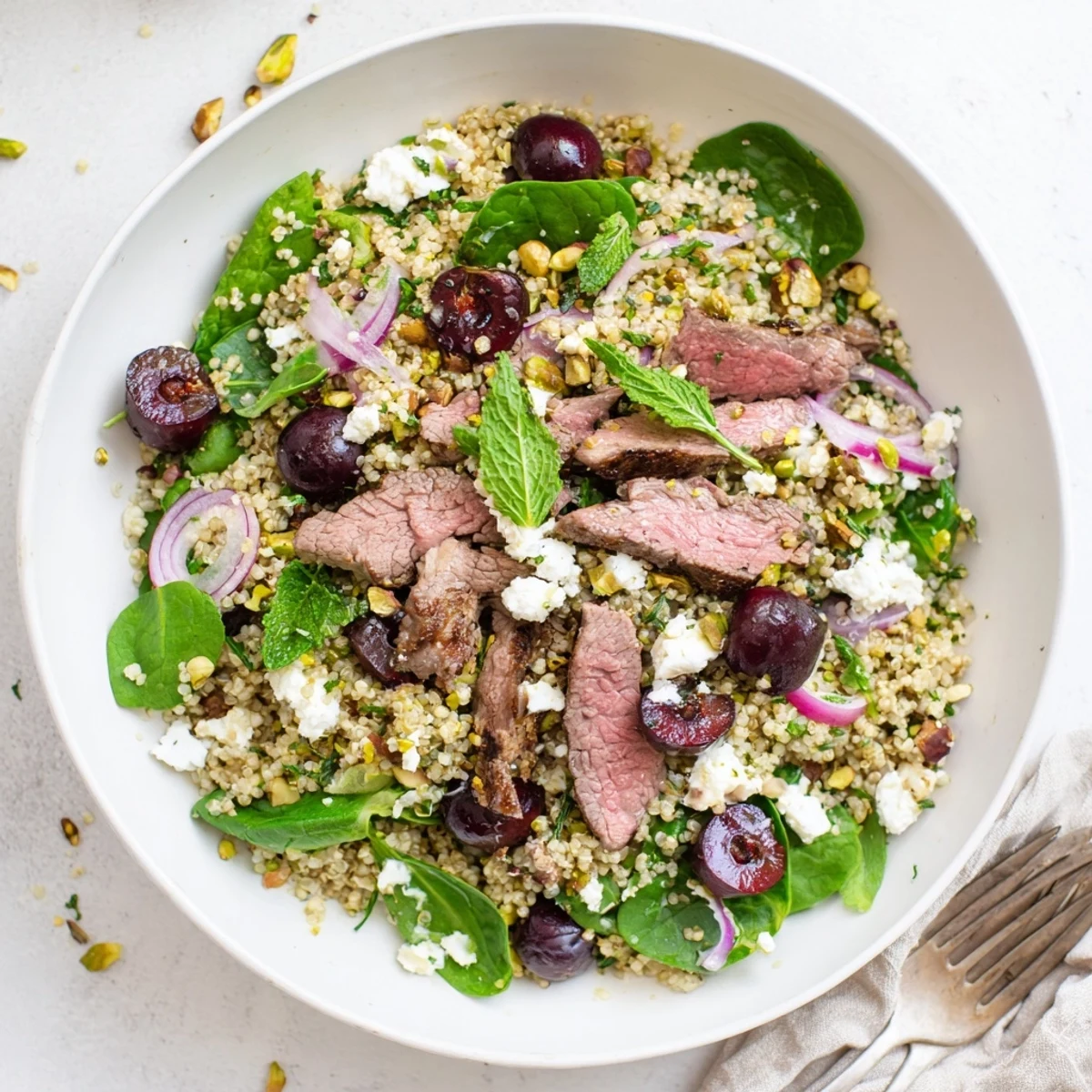 Golden seared lamb atop fluffy quinoa salad with sweet cherries, pistachios, and fresh mint