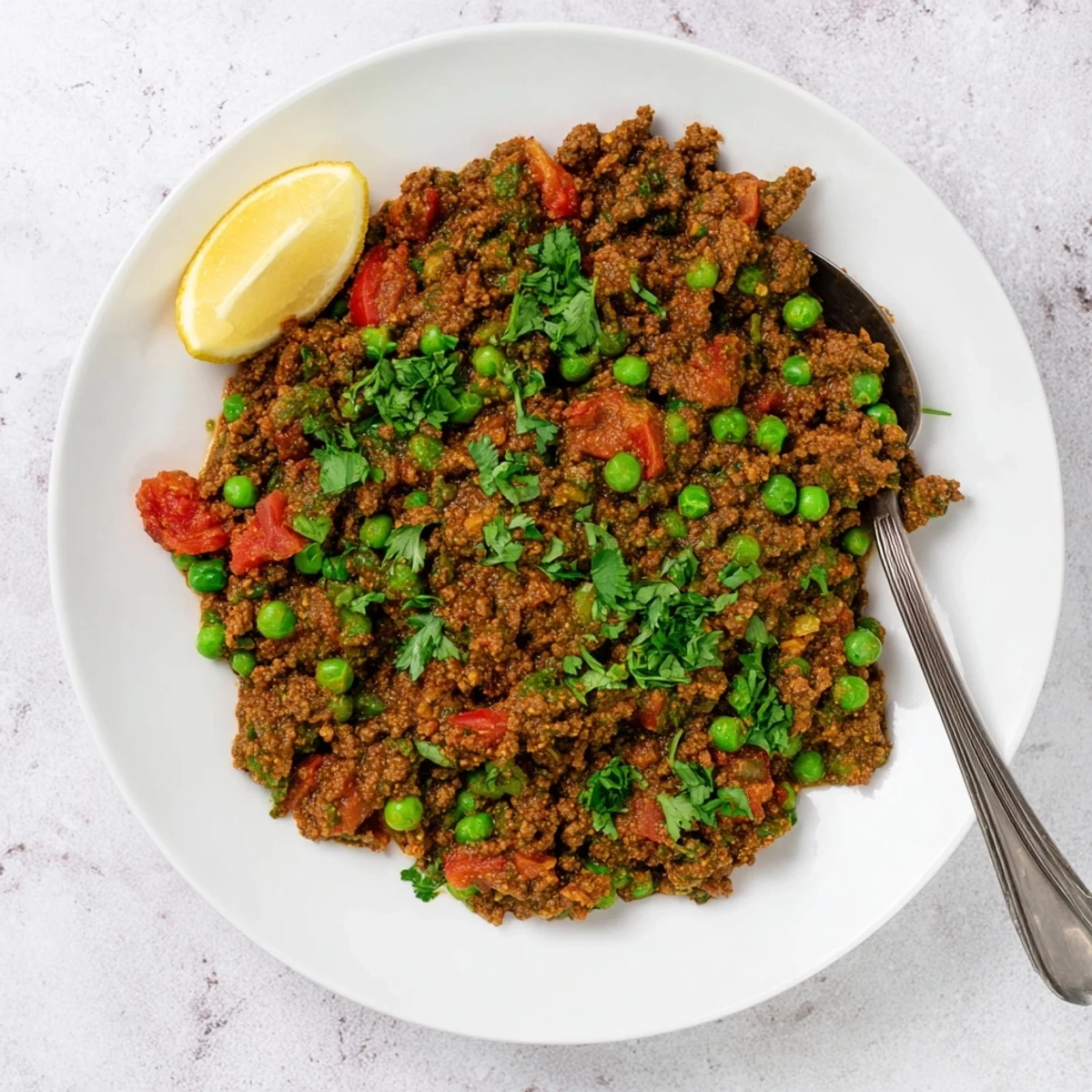 Steamy bowl of Indian Keema Curry garnished with fresh cilantro alongside fluffy white rice
