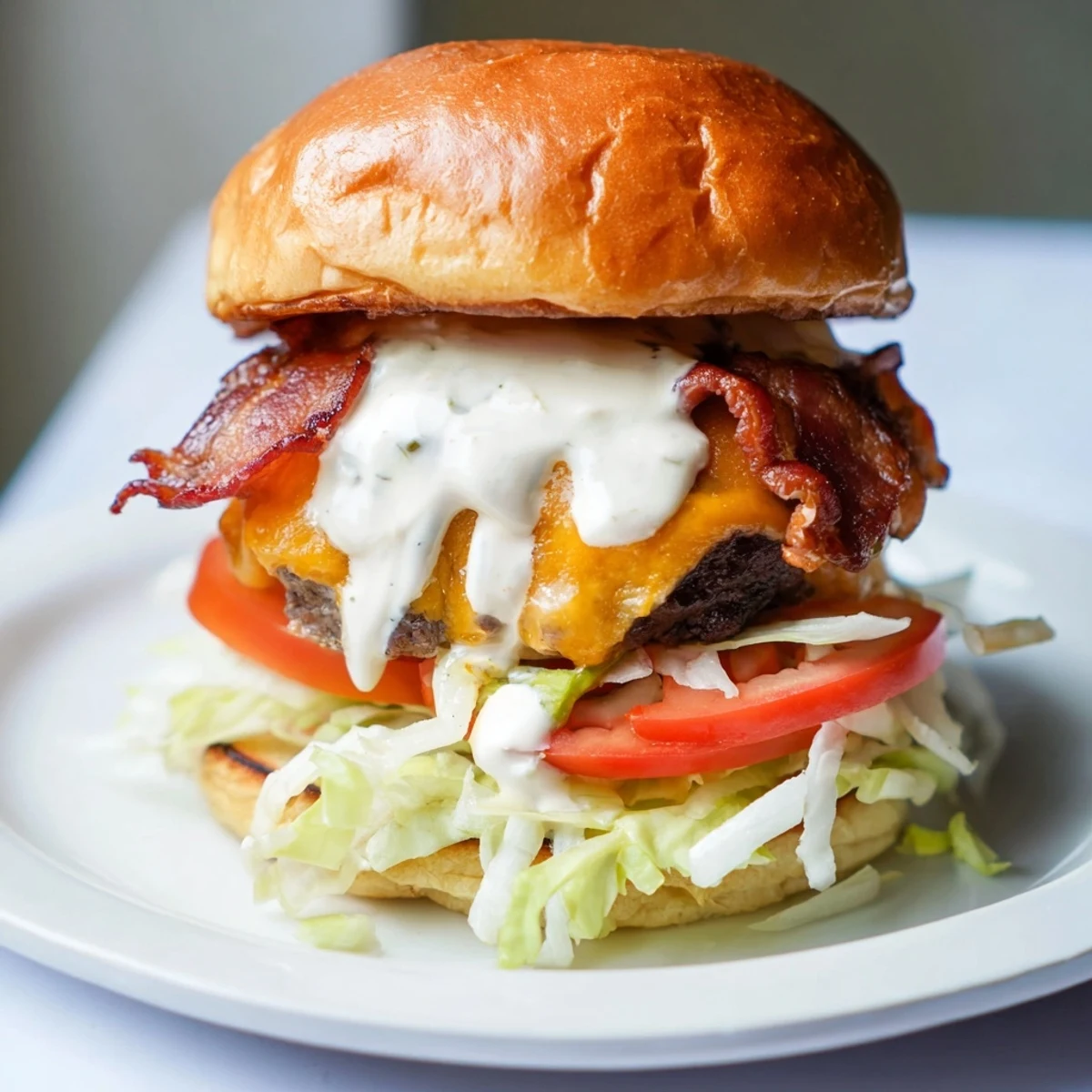 Juicy crack burger stacked with crispy bacon, melted cheddar, and creamy white sauce on toasted brioche bun