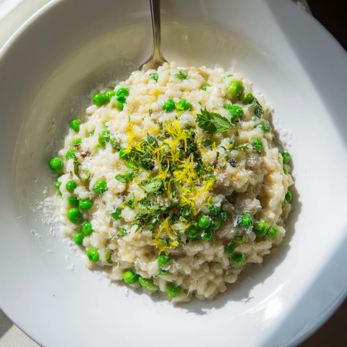 Close-up of creamy spring pea risotto showcasing tender peas and Arborio rice texture with Parmesan shavings