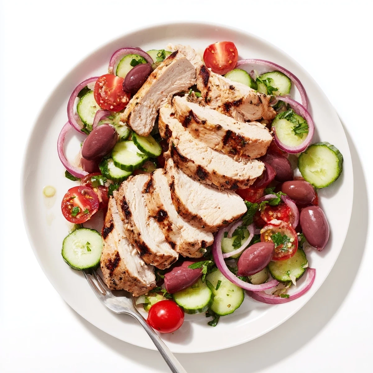 Golden grilled Fiery Mediterranean Chicken served atop crisp cucumber salad with cherry tomatoes and olives