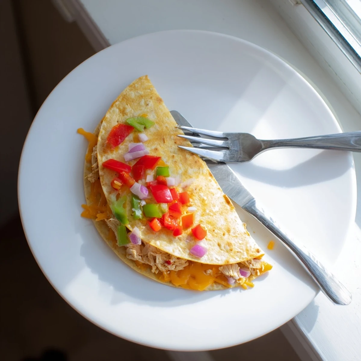 Homemade chicken quesadillas with red and green peppers, garnished with fresh cilantro and lime wedges