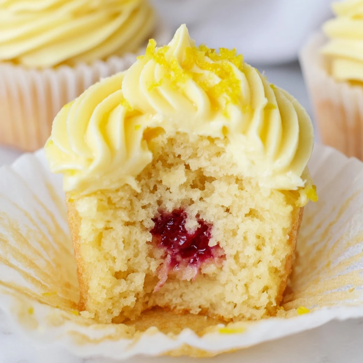 Yellow lemon cupcakes filled with tangy raspberry preserves and swirled with creamy lemon frosting