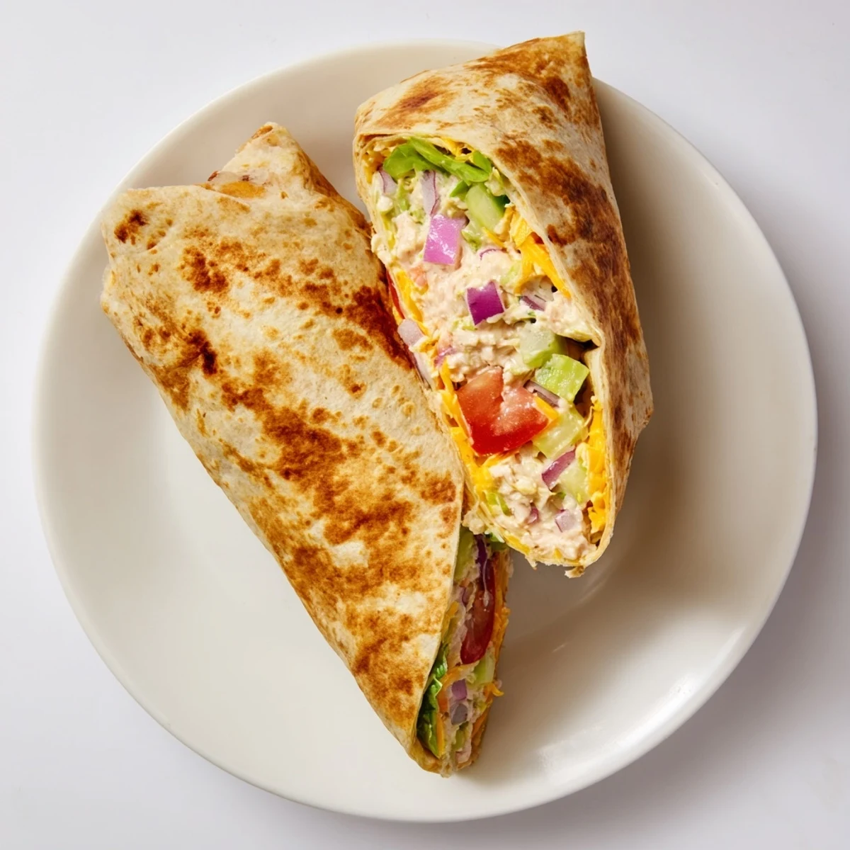 Golden grilled tuna melt wrap sliced in half revealing creamy tuna salad and melted cheddar cheese