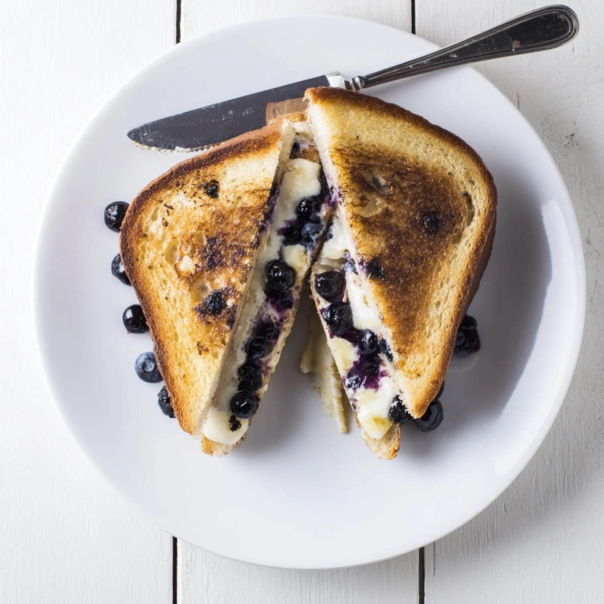 Pan-fried blueberry grilled cheese sandwich with crisp buttery bread and warm berry filling