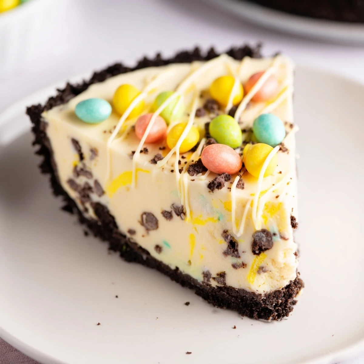 Creamy Easter Egg Cheesecake slice topped with colorful mini chocolate eggs on white plate