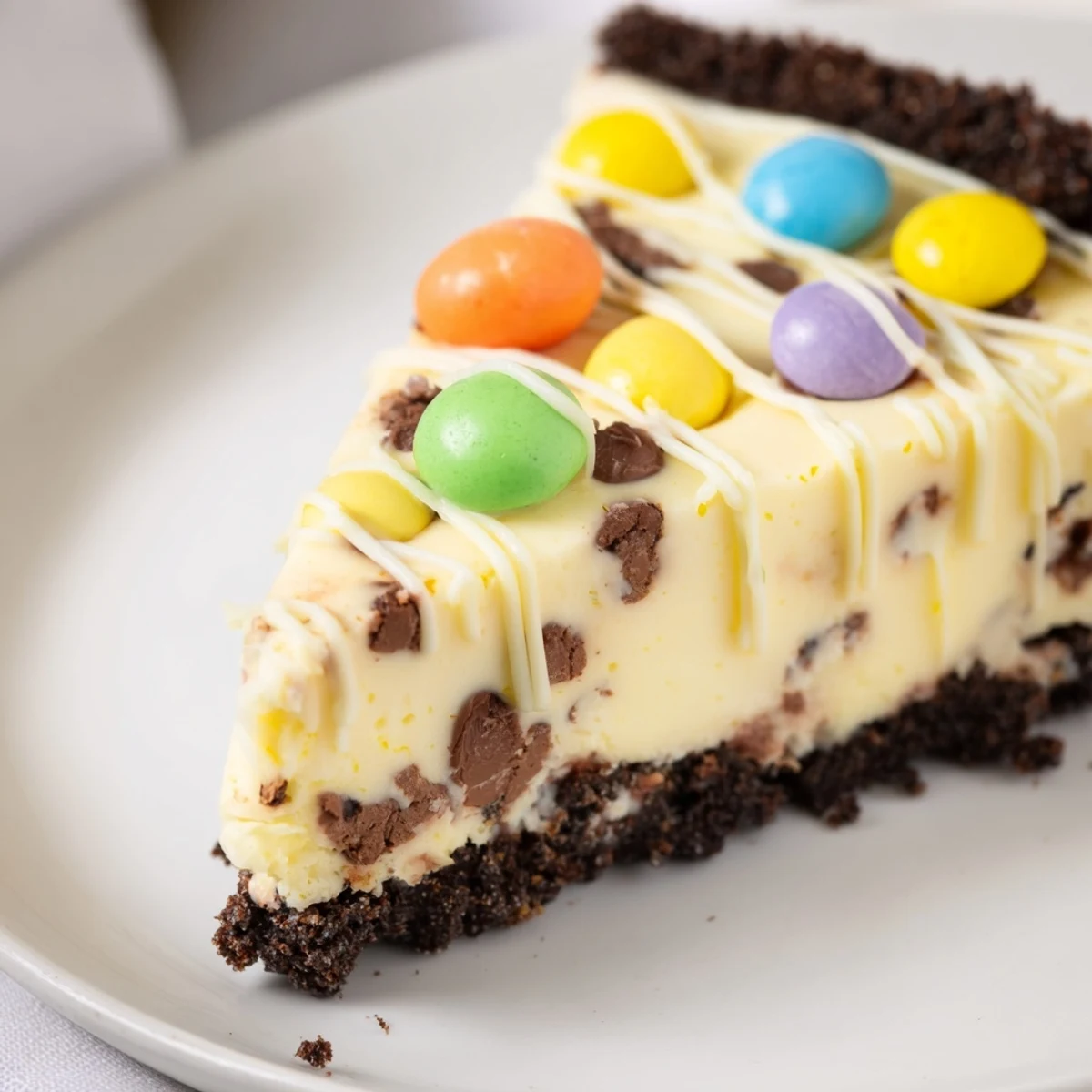 Velvety smooth Easter Egg Cheesecake drizzled with white chocolate and festive egg toppings