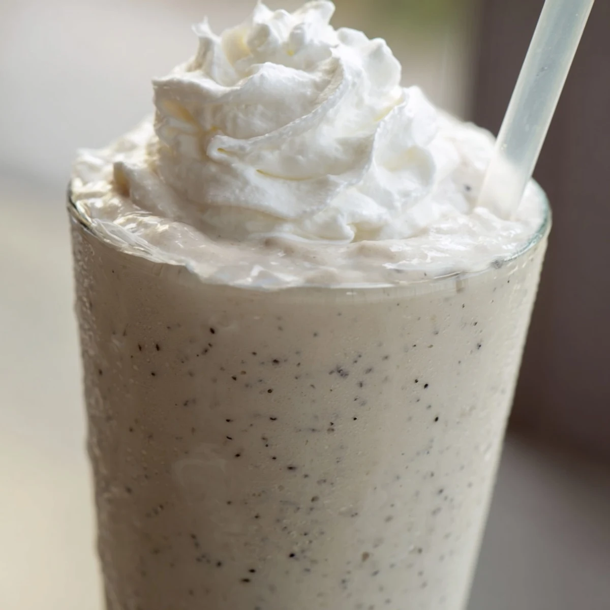 Frosty blended vanilla bean frappuccino with ice crystals swirling throughout the white beverage