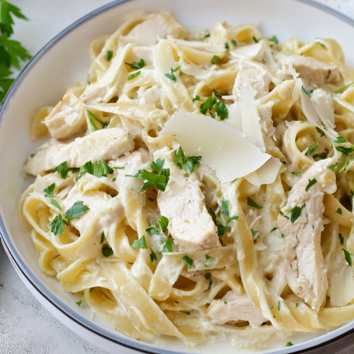 Creamy garlic parmesan chicken pasta twirled on a white plate garnished with fresh parsley.